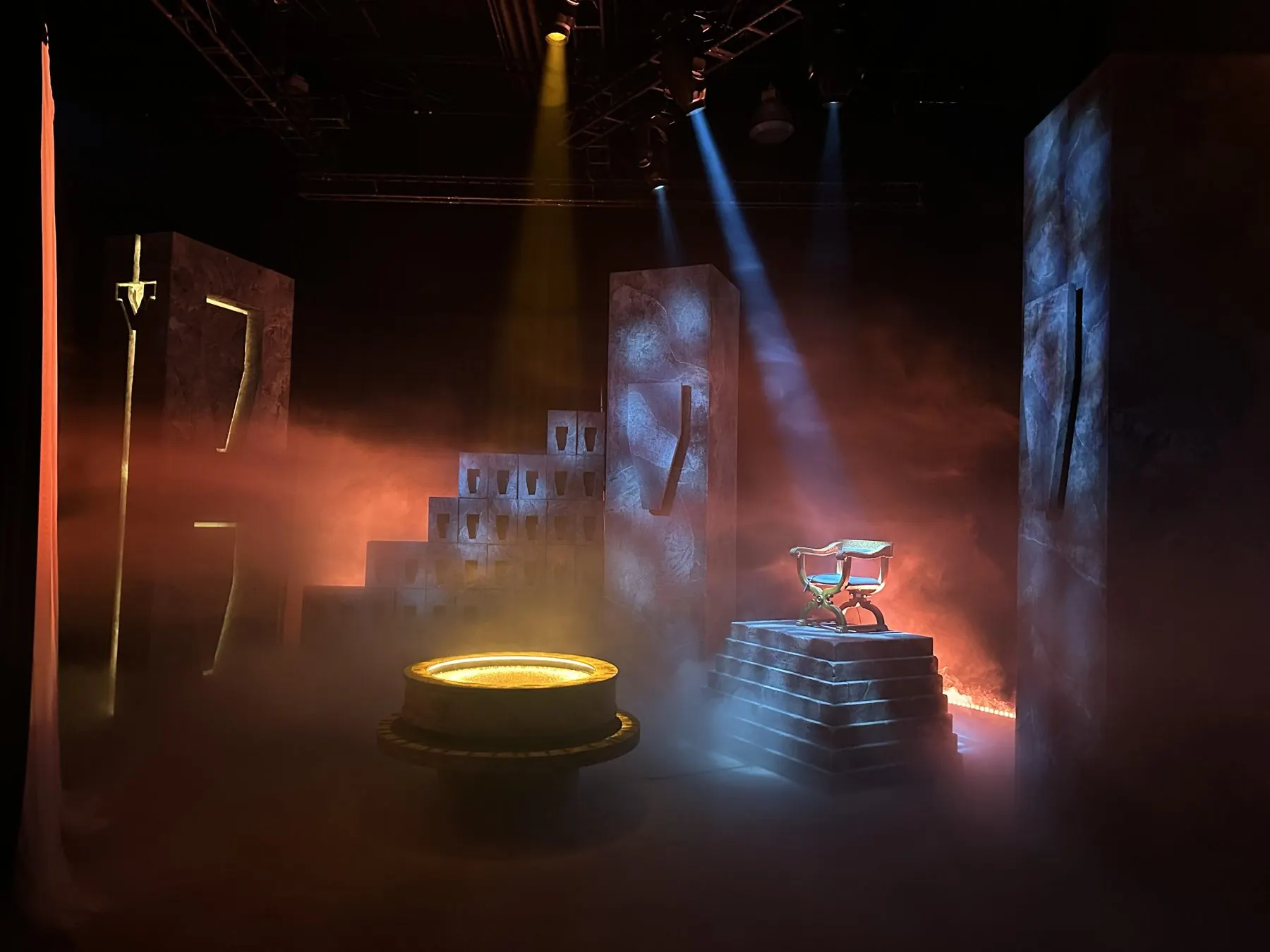 A theatrical stone set with a throne, haze and moving-light beams